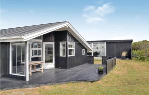 a black house with a deck in a yard at 4 Bedroom Stunning Home In Hvide Sande in Hvide Sande