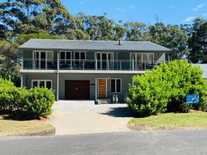 une maison verte avec un balcon au-dessus dans l'établissement Huskisson Beach Bed and Breakfast, à Huskisson