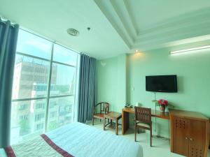 a hotel room with a bed and a desk and a television at Khách sạn Trường Sơn in Ho Chi Minh City