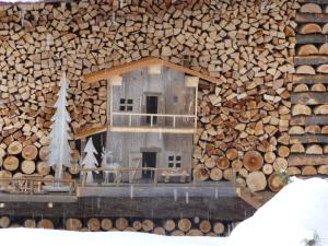ein Modell eines Blockhauses vor einem Stapel von Stämmen in der Unterkunft Alla Frasca Verde in Lauco