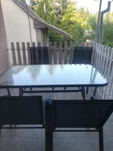 szklany stół i krzesła na patio w obiekcie G&G APARTMANOK w mieście Igal