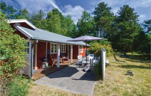 uma casa vermelha com um pátio com um guarda-chuva em Awesome Home In Hjby With Kitchen em Højby