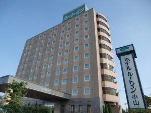 een hotelgebouw met een bord ervoor bij Hotel Route-Inn Oyama in Oyama