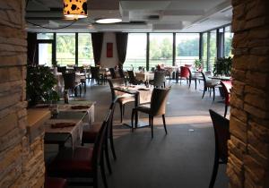 a dining room with tables and chairs and windows at Hôtel Spa les Alizés in Lipsheim