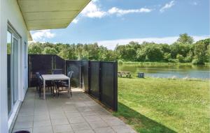 a patio with a table and chairs and a view of a river at Holiday Home Dyrefolden Ringkøbing Iv in Hee