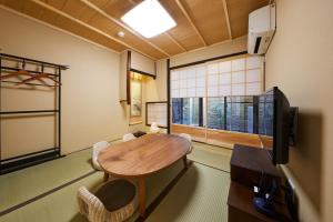 - un salon avec une table en bois et une télévision dans l'établissement Rinn Tenjincho, à Kyoto