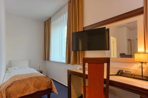 a hotel room with a bed and a flat screen tv at Centro Hotel Celler Tor in Braunschweig