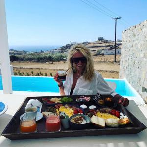 a woman sitting at a table with a tray of food at The Ammonite Resort in Super Paradise Beach