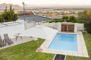 an outdoor pool with an umbrella and an umbrella at Somerset View Guest House in Somerset West