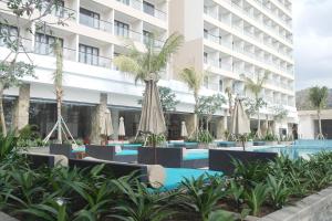 a hotel pool with umbrellas and palm trees at Louis Kienne Resort Senggigi in Senggigi