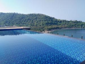 a large swimming pool next to a body of water at Louis Kienne Resort Senggigi in Senggigi