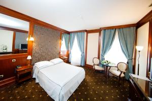 a hotel room with a bed and chairs and windows at Hotel Select in Iaşi