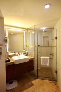 a bathroom with a sink and a shower with a mirror at Hotel Landmark Canton in Guangzhou