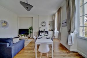 a living room with a white table and a blue couch at Le Joyau by Cocoonr in Bordeaux