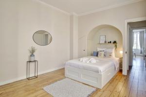 um quarto branco com uma cama branca e um espelho em Le Joyau by Cocoonr em Bordéus