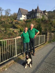 a man and woman standing next to a fence with a dog at Plas Penaeldroch Manor in Dolwyddelan