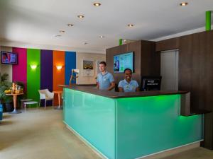 two men standing at a colorful counter in a room at ibis Styles Le Puy en Velay in Le Puy-en-Velay