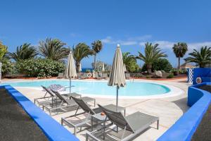 una piscina con tumbonas y sombrillas en Hotel LIVVO Risco del Gato Suites en Costa Calma