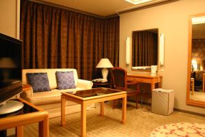 a living room with a couch and a desk in a hotel room at Kakegawa Grand Hotel in Kakegawa