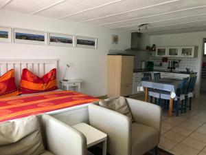een slaapkamer met een bed en stoelen en een keuken bij Chalet Murmeli in Eigenthal