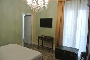 1 dormitorio con cama, mesa y TV en Palazzo Zecchino B&B, en Génova