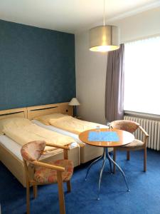 1 Schlafzimmer mit 2 Betten, einem Tisch und Stühlen in der Unterkunft Der Quellenhof in Helmstedt