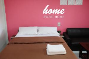a bedroom with a bed and a couch and a pink wall at NK Garden Hotel @Suratthani Airport in Suratthani