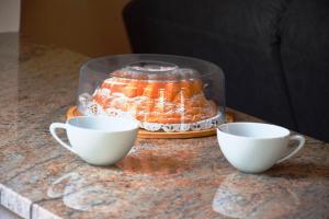 a table with two cups and a cake in a glass container at O Mencer do Camiño in Cee