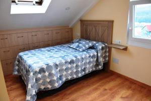 a bedroom with a bed with a blue and gray blanket at O Mencer do Camiño in Cee