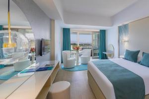 a hotel room with a bed and a table and chairs at Ivi Mare - Designed for Adults by Louis Hotels in Paphos