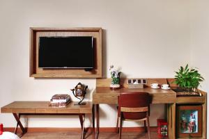 een televisie aan de muur met een bureau en een stoel bij James Joyce Hotel Xi'an Datang Furong Garden in Xi'an
