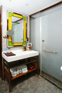 een badkamer met een wastafel, een spiegel en een douche bij James Joyce Hotel Xi'an Datang Furong Garden in Xi'an
