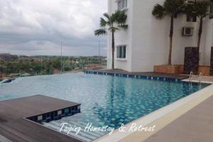 a large swimming pool next to a building with palm trees at Taiping Centre Point Suite 10 by BWC in Taiping