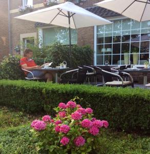 Hotel Pension Oranje في فالكنبورخ: امرأة تجلس على طاولة تحت مظلة