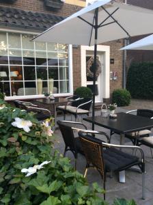 eine Terrasse mit Tischen, Stühlen und einem Sonnenschirm in der Unterkunft Hotel Pension Oranje in Valkenburg
