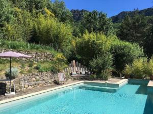 a swimming pool in a yard with trees and a mountain at Les SenS de l'Escalette in Pégairolles-de-lʼEscalette