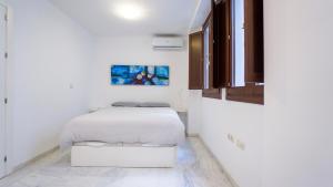 a white bedroom with a white bed and cabinets at RentalSevilla Espacioso dúplex en la Puerta Real in Seville