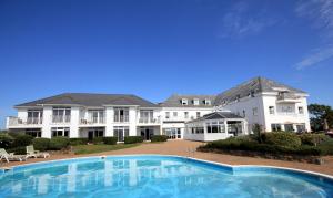a large house with a large swimming pool in front of it at Hotel Jerbourg in St Peter Port