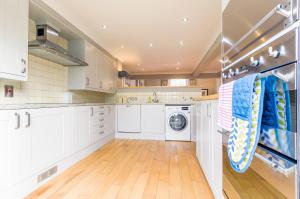 a kitchen with white cabinets and a washer and dryer at Luxury Apartments - 10 Royal Parade in Cheltenham