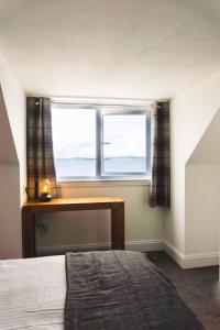 1 dormitorio con cama, escritorio y ventana en THE BRUCE en Bowmore