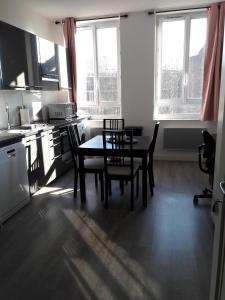 eine Küche mit einem Tisch, Stühlen und Fenstern in der Unterkunft Studio Molinel in Lille