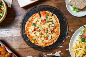a pizza on a plate on a table with fries at Safestay Madrid Central in Madrid