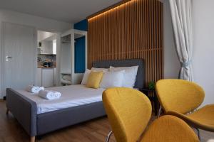 a bedroom with a bed with two yellow chairs at Adel Apartments in Veliko Tŭrnovo