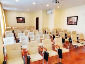 a room with rows of white chairs and tables at Hotel Metropolis in Surgut