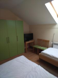 1 dormitorio con armarios verdes, 1 cama y TV en Pansion Ribnjak, en Našice