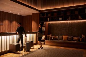 a man and a woman standing in a lobby with a suitcase at Nest Hotel Tokyo Hanzomon in Tokyo