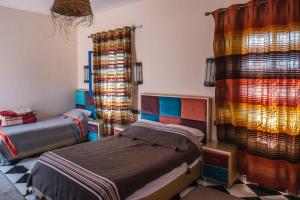 1 dormitorio con 2 camas y cortinas coloridas en La Petite Kasbah en Zagora