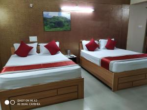two beds in a hotel room with red pillows at Hotel Surya Residency Majestic in Bangalore