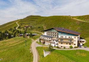 ein großes Haus auf einem Hügel mit einer Straße in der Unterkunft Mountainlovers Berghotel SeidlAlm in Saalbach-Hinterglemm