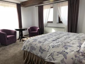 ブランにあるBran Monte Crai Chaletのベッドルーム1室(ベッド1台、椅子2脚付)